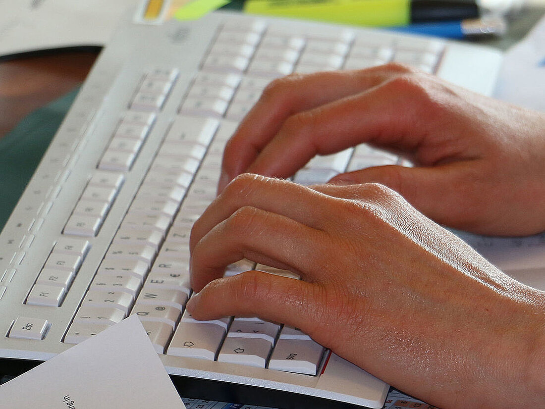 Zwei Hände auf einer Computertastatur.