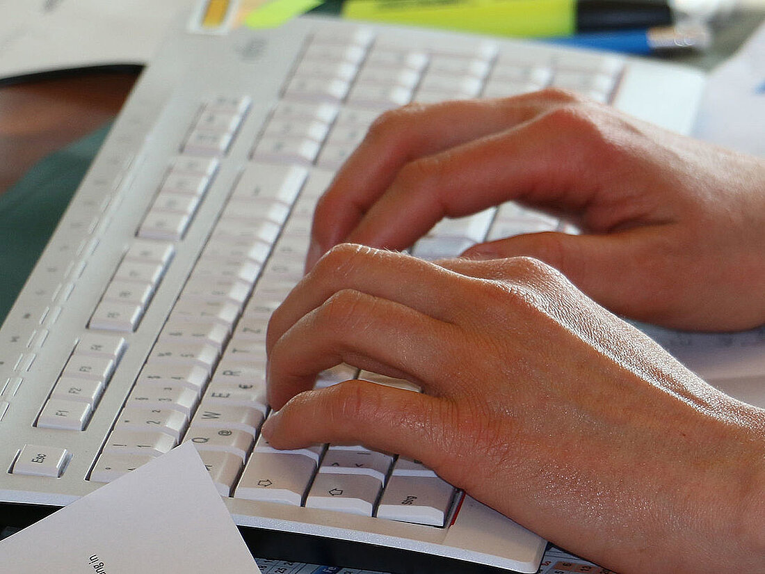 Hände schreibbereit auf Computertastatur