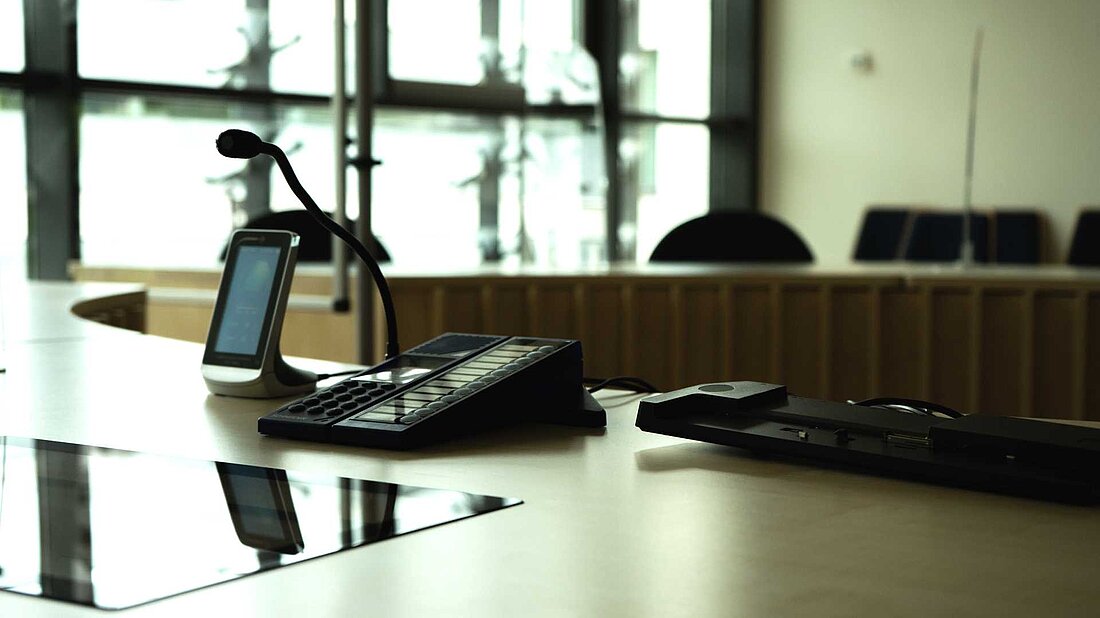 Die Richterbank eines Sitzungssaals aus Sicht des Richters mit technischer Ausstattung.