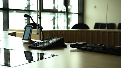 Die Richterbank eines Sitzungssaals aus Sicht des Richters mit technischer Ausstattung.